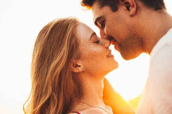 Ritratto ravvicinato di una donna e di un uomo che chiudono gli occhi e vogliono baciarsi con il sole che splende dietro di loro. Vista laterale. Ritratto ravvicinato. — Foto Stock