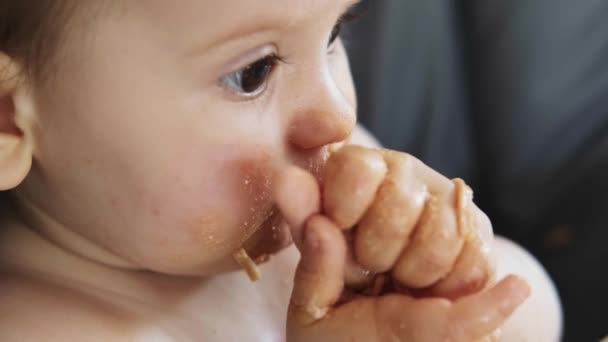 Close-up view of a baby girl licking her fingers after a tasty meal. Beautiful portrait. Baby development. Close-up portrait. — Stock Video