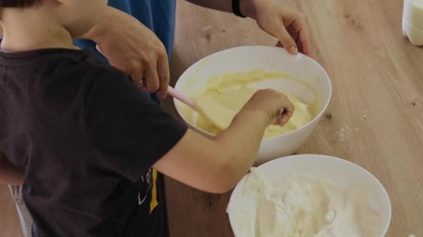 Boy adding with a spoonful of whipped cream, in the cream cheese that my mother prepares for the cakes. For celebration design. Adding ingredients. — Stock video