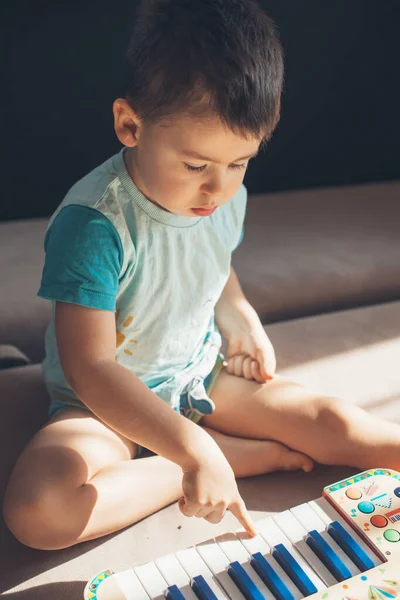 Little boy playing electrical toy piano on floor. Early development for toddler and baby — Fotografia de Stock