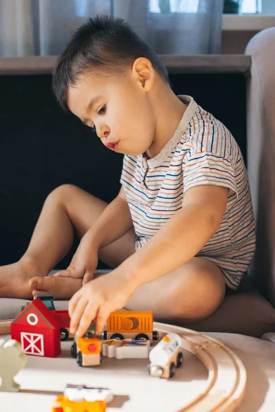 Caucasian little boy playing with a railroad train toy sitting on the floor in the living room. Playtime. — Fotografia de Stock