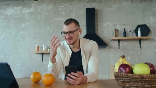 Mattinata trascorsa da un uomo in cucina a discutere di business plan con i colleghi usando il suo telefono e tablet. Comunicazione senza fili. — Video Stock