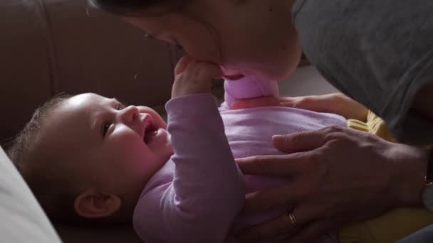 Mother playing with her baby in the bedroom. Mother kissing babys stomach while lying on bed. — Stock Video