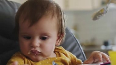 Baby refusing to eat the spoon of porridge spread by the mother. Healthy food. Baby care. Beautiful portrait. Family care.