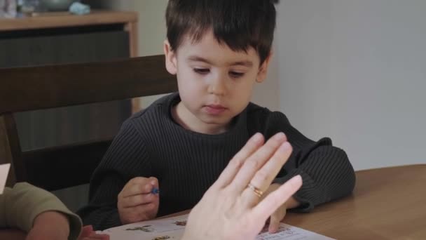 Mothers hand showing the boy how to solve the exercise correctly. Studying, doing homework. — Stock video