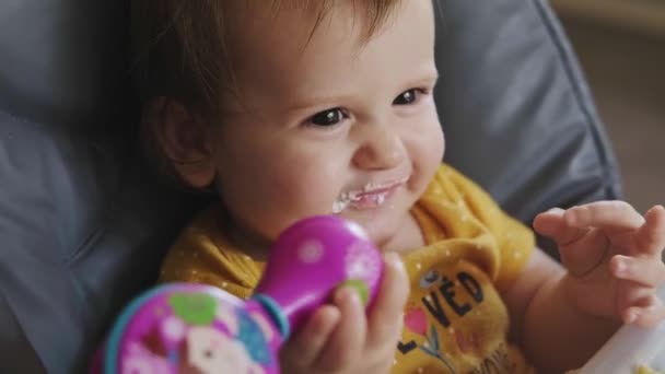 Küçük kız oyuncağıyla oynarken annesi tarafından kaşıkla besleniyor. Güzel bir portre. Bebek bakımı. Sağlık hizmetleri. Yakın plan portre. — Stok video