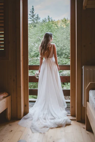 Vista trasera de una novia de pie esperando a su novio en el balcón admirando la naturaleza. Naturaleza paisaje. Belleza, moda. Estilo elegante. —  Fotos de Stock