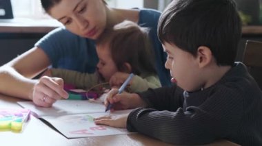 Mother tutor holding baby girl, teaching to write his son. Education, learning, study. Homework assignment. Coronavirus school.