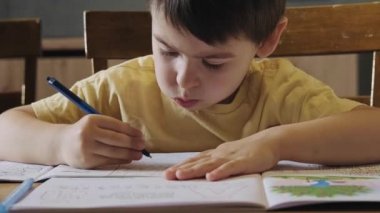 Yazmaktan yorulan çocuk kameraya baktı ve konuşmaya başladı. Ön manzara. Mutlu aile tatilleri. Aile Günü.