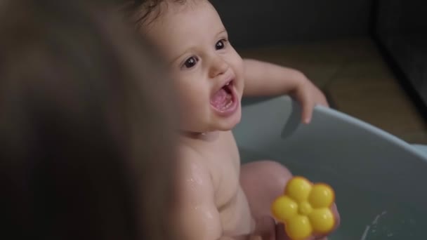Beautiful baby girl bathing in a bathtub with a toy. Baby care. Funny baby girl playing with water. — Vídeo de Stock