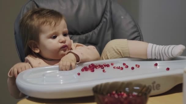 Stół dla niemowląt pełen nasion granatu, dziecko siedzące wygodnie i jedzące zdrowo. Rozwój dziecka. Zdrowy letni owoc. Zdrowa dieta. — Wideo stockowe