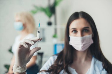 Close up portrait of a nurse in a protective mask holding a prick looking at camera. Medical treatment. Coronavirus prevention. Coronavirus pandemic. Holding