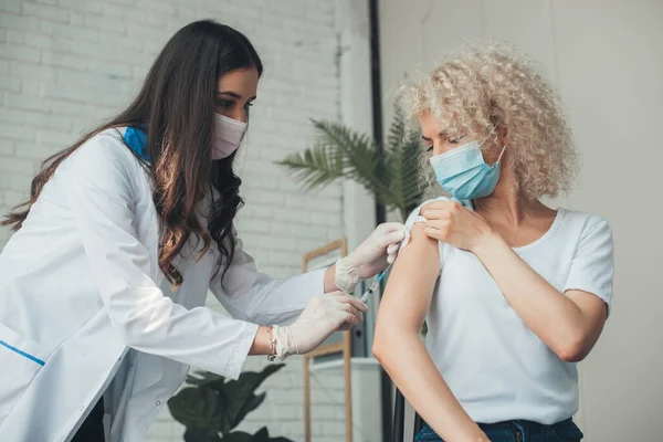 Medico in guanti medici e maschera che somministra l'iniezione al paziente durante la campagna di vaccinazione in ospedale. Assistenza sanitaria. Corona viru Protezione da virus. Medico — Foto Stock