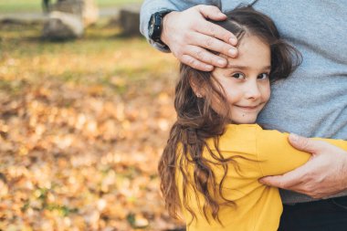 Gülümseyen kız, babayı kucaklıyor kameraya bakıyor ve parkta birlikte vakit geçiriyorlar. Mutlu aile birlikte. Mutlu aile tatilleri. Etkinlik ilişkisi