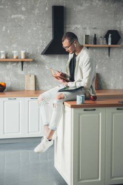 Adam zoom video konferans görüşmesi yaparken notlar alıyor, mutfakta oturuyor. Uzaktan kumanda. Modern iletişim.