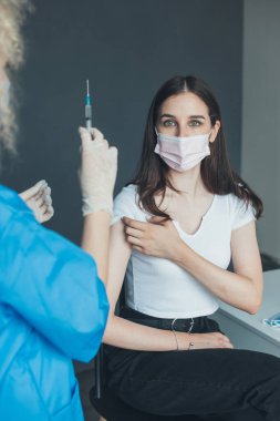 Kafkas hastası Coronavirus enjeksiyonuna karşı aşılanmaya hazırlanıyor, bir hastanede bir doktor tarafından. Bağışıklık. Kolunda grip aşısı var.