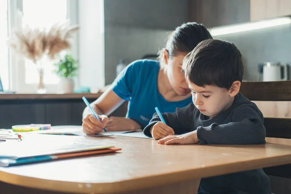 Madre Hijo Escribiendo Bloc Notas Mientras Están Sentados Juntos Mesa —  Fotos de Stock