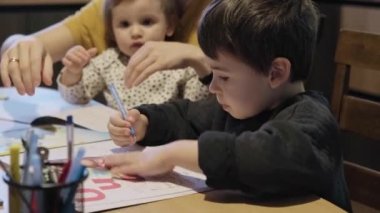 Anne bebeğini kollarında tutuyor, oğluna ödevlerinde yardım ediyor, mutfakta masada oturuyor, okuyor, yazıyor ya da çiziyor, evde eğitim veriyor. Karantina, salgın hastalık