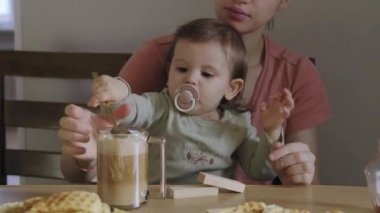Anne bebeği kollarında tutuyor ve birlikte kahvaltı ediyor. Güzel bir anne bebeğiyle kahvaltı yapıyor. Her şey için harika bir tasarım. İnsanlar