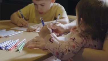 Onlar çizim yaparken anne çocuklarıyla evde oturuyor. Anne ve oğlu evde ödev yapıyor. Annesi küçük çocuğun ödevlerini yapmasına yardım ediyor.