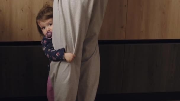台所に立って 彼女のお母さんから注目を集めたい赤ちゃんの女の子をクリニー 顔の表情 赤ん坊の女の子のためにピックアップを求めて — ストック動画