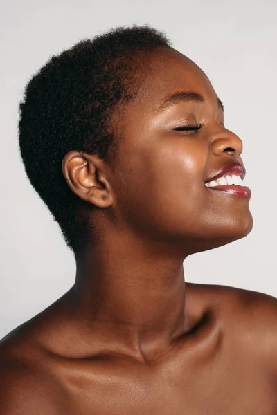 Profile, half face portrait of naked attractive afro woman enjoying her perfect skin with close eyes, posing over white background. Spa body care.Cosmetology