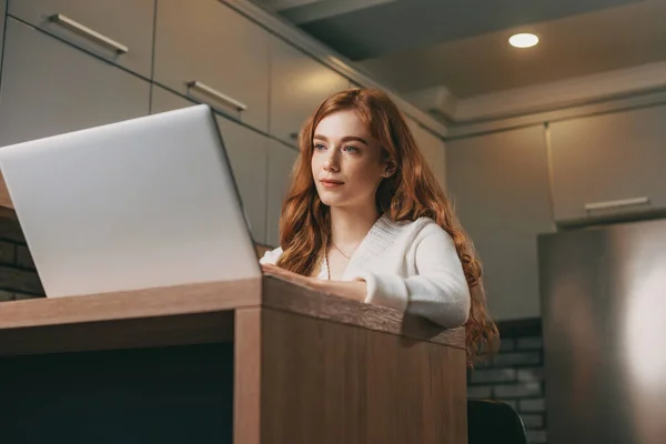 Masada Dizüstü Bilgisayarıyla Oturan Kızıl Saçlı Genç Kadın Internette Çalışıyor — Stok fotoğraf