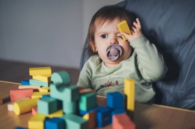 Küçük kız oyuncaklardan kule inşa ediyor. Bebek gelişimi. Küçük çocuklar için eğitici ve yaratıcı oyuncaklar ve oyunlar.