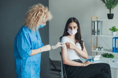 Hemşire elinde şırıngayla hastalara tıbbi maske takmadan önce pamuk kullanıyor. Bağışıklığı uyaran COVID 19 aşısı.