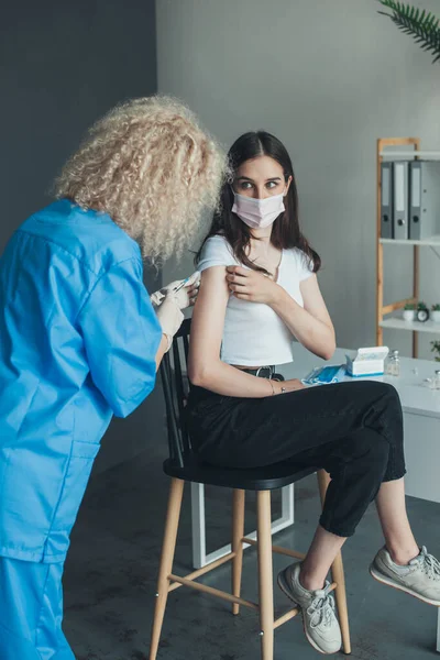Hemşire koruyucu maske ve eldiven takarak hastaya aşı enjekte ediyor. Aşı ve sağlık hizmetleri. Coronavirus konsepti