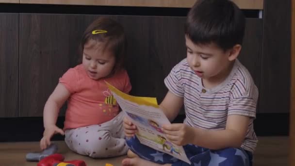 Hermano Hermanita Trabajando Juntos Siguiendo Libro Instrucciones Para Poder Jugar — Vídeo de stock