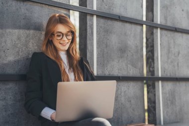 Serbest çalışan iş kadını parkta bankta otururken dizüstü bilgisayar kullanıyor. Modern internet iletişimi. İnternet teknolojisi.