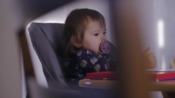 赤ん坊の女の子はハイチェア遊びに座って 自宅でペースメーカーを吸います 人々のライフスタイルの概念 健康食品 ベビーケア — ストック動画