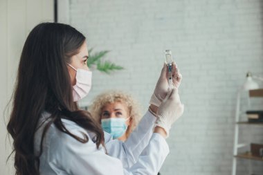 Nurse drawing medication out of vial before giving injection to patient, in the hospital. Coronavirus vaccination. Coronavirus prevention. Pandemic prevention.