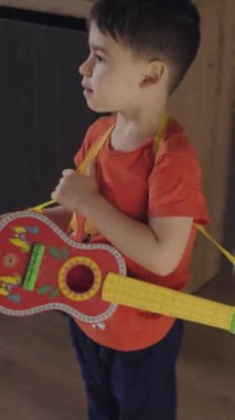 Küçük gitarlı küçük bir müzisyen çocuk, evde boş vaktinin tadını çıkarıyor. Güzel portre.