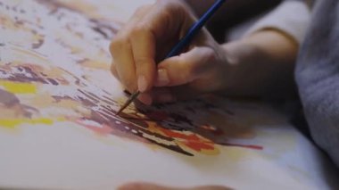 Close-up portrait of a womans hands drawing with a brush painting by numbers on canvas. Creative hobby. Painting for beginners. Leisure activity for stay home