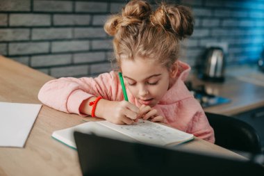 Liseli kız, masada oturup ödevini tablet bilgisayar kullanarak yapıyor. Öğrenim, uzak öğrenim, çevrimiçi eğitim.