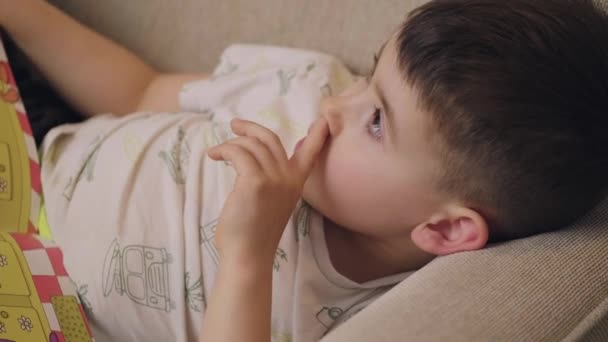 Caucasian Boy Child Picking His Nose While Reading Book Sitting — Αρχείο Βίντεο