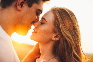 Close-up portrait of a caucasian couple kissing during their date against sunset light, outside. Romantic relationship concept. Love, romance concept. Nature