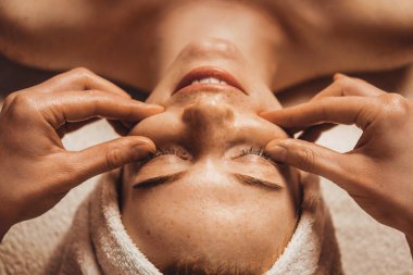 Masaj terapisti müşterilerin yüzüne elle masaj yapıyor. Sağlıklı yaşam tarzı kavramı. Kozmetoloji konsepti. Güzel surat..