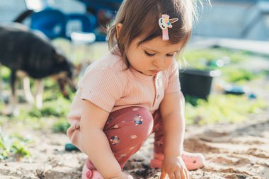 Evin bahçesindeki kumda oynayan küçük kız bahçede ne olduğunu merak ederek keşfediyor. Bebek kum kalıplarıyla oynuyor. Açık havada yaratıcı faaliyetler