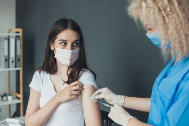 Tıbbi maskeli beyaz kadın hastanede aşı kampanyası sırasında COVID-19 vuruluyor. Koronavirüs ya da gribi önlemek için. Corona virüsü kavramı