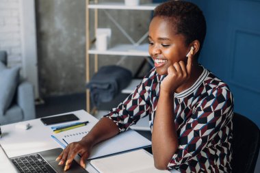 Black woman working from her office using laptop to participate video conference calling. Call center operator. Looking away and communicating