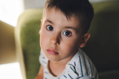 The portrait of a boy looking sadly straight into the camera. Head shot portrait. Little pretty preschooler boy. Lovely kid.