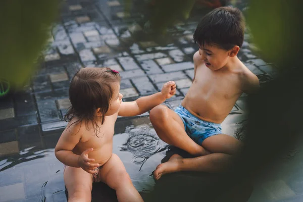 Happy brother and sister playing and splashing with water on summer. Summer vacation fun. Funny spring holiday. Happy family, childhood.