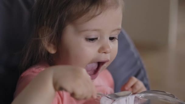 Baby Girl Sitting High Chair Eating Yoghurt Spoon Her Big — Stock Video