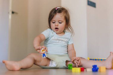 Happy baby girl building something from colorful toy bricks and blocks. Playing together, enjoying leisure, playtime