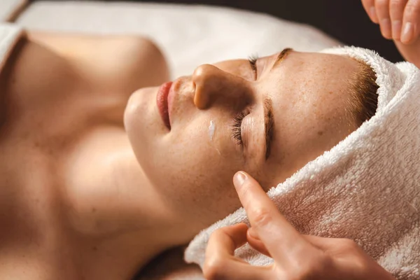 Caucasian freckled woman having face massage in a spa salon. Beauty treatment. Attractive elegant woman. Spa treatment.