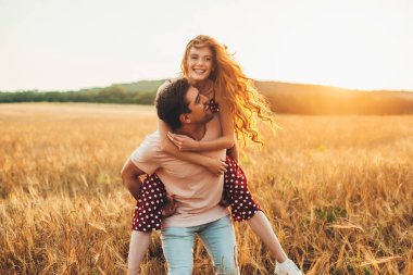 Caucasian man giving the girl a piggy back ride as they smile at the camera while enjoying a day in the country. Harvesting agriculture and plantation concept