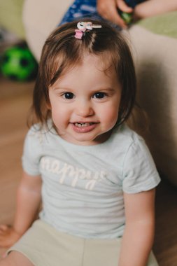 Smiling baby girl playing sitting on the floor and looking at camera. Happy family, childhood. Newborn baby care concept. Smiling happy child. Smiling girl.